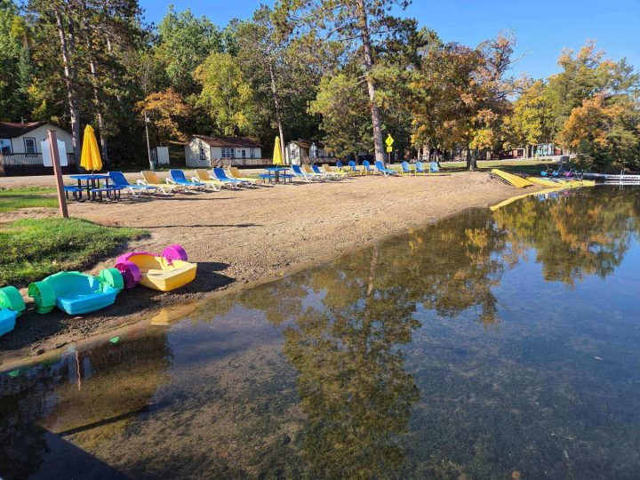 Sandy lakeside resort beach with colorful chairs and paddle boats