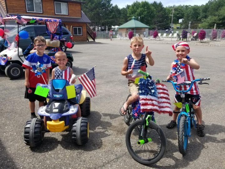 Four kids celebrating Fourth of July with decorated bikes and toys