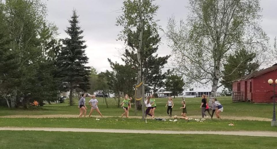 Girls playing outdoor volleyball on a grassy field