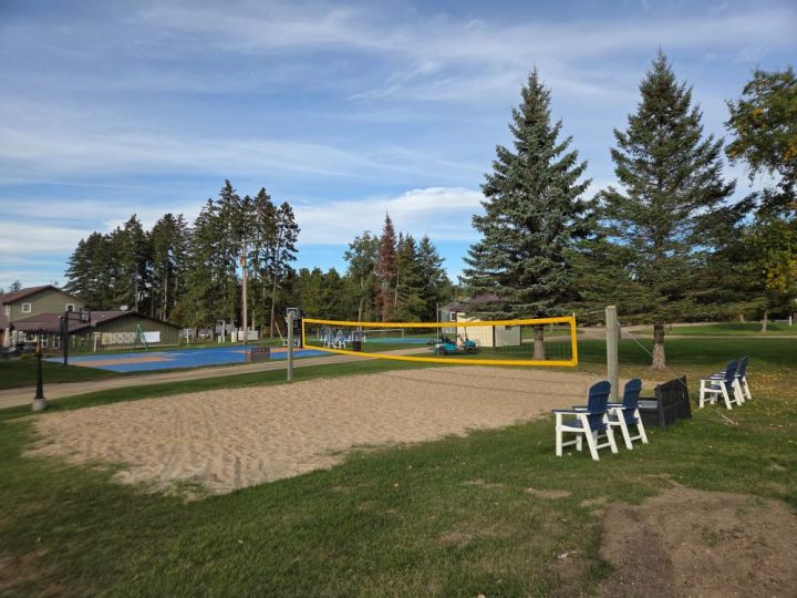 Outdoor sand volleyball court with yellow net and seating area